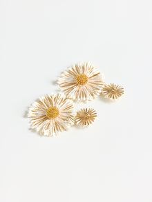 Four white and yellow dried daisies arranged on a plain background, evoking the sculptural elegance and delicate beauty of the Daisy Cluster Earrings by Social Queen.