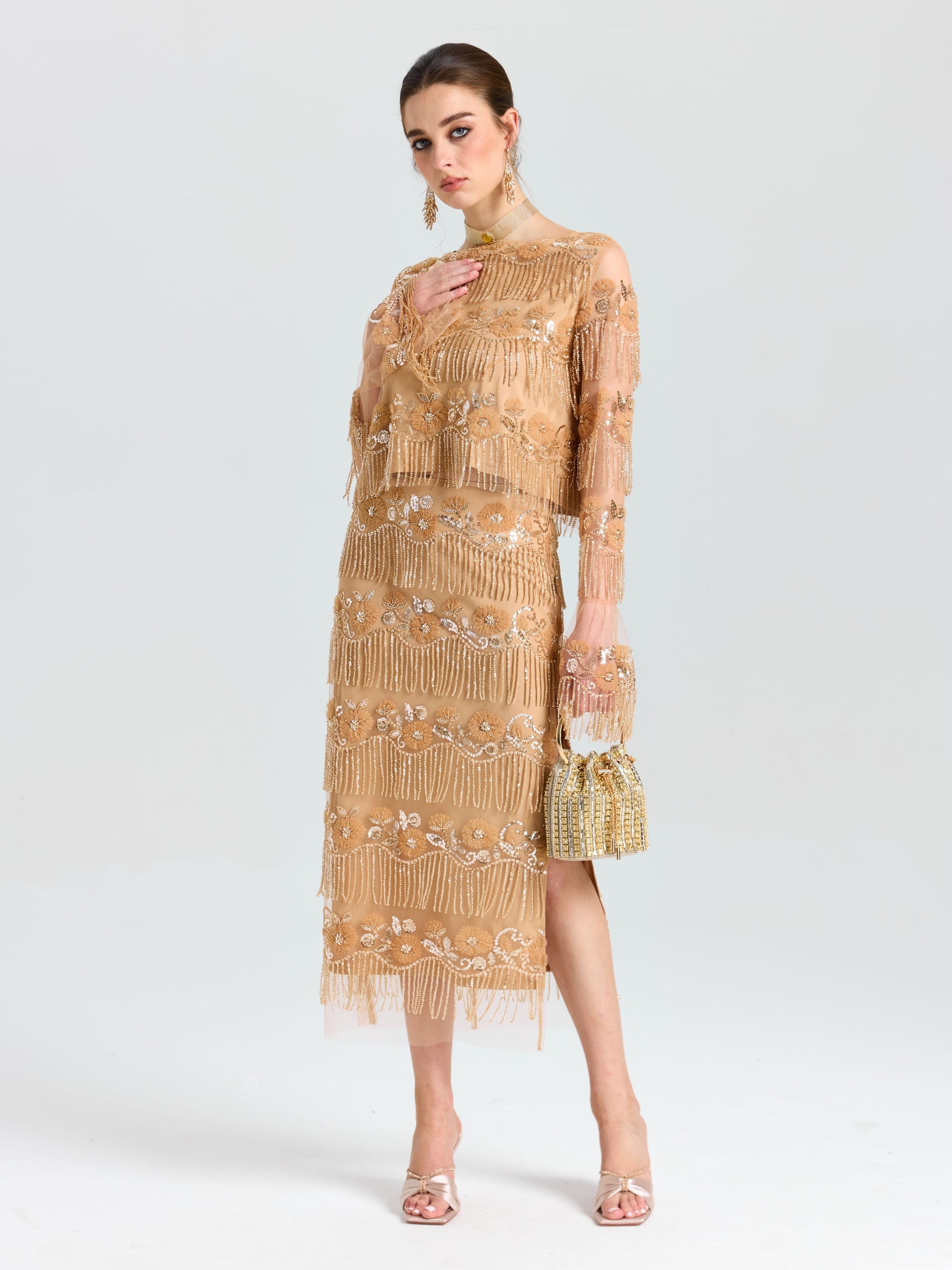 A woman wearing the Social Queen Beaded Fringe Slit Midi Skirt, paired with heeled sandals and a beaded handbag, stands against a plain light background.