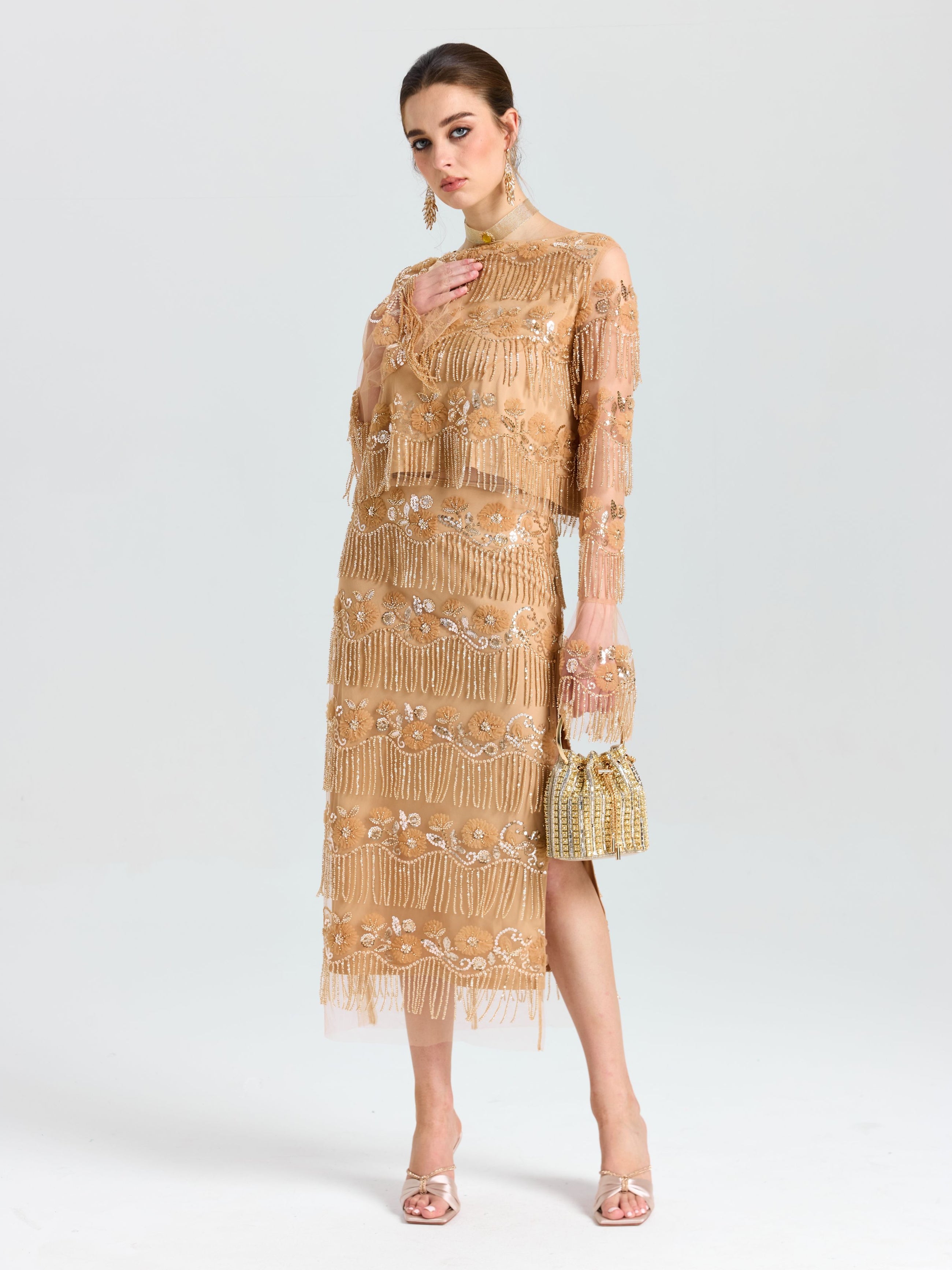 A woman wearing the Social Queen Beaded Fringe Slit Midi Skirt, paired with heeled sandals and a beaded handbag, stands against a plain light background.