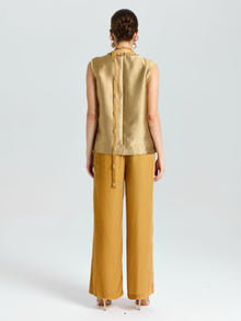 A woman faces away, wearing Social Queen’s Velvet Scarf Silk Organza Top (Cami Included) and loose mustard-yellow pants, set against a plain light background.