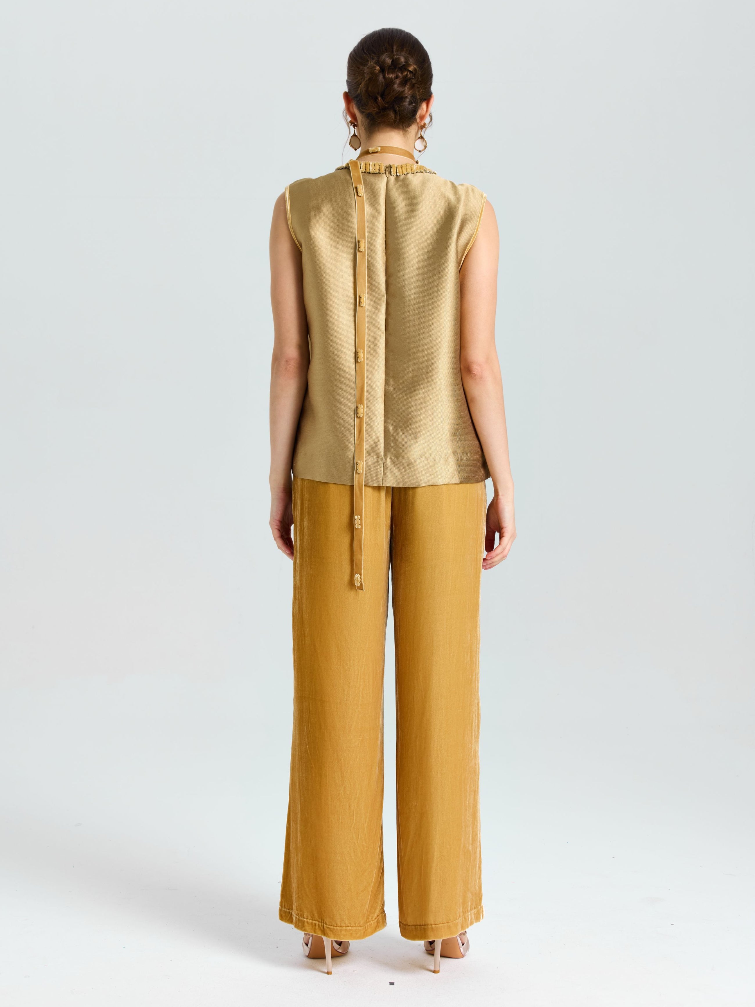 A woman faces away, wearing Social Queen’s Velvet Scarf Silk Organza Top (Cami Included) and loose mustard-yellow pants, set against a plain light background.