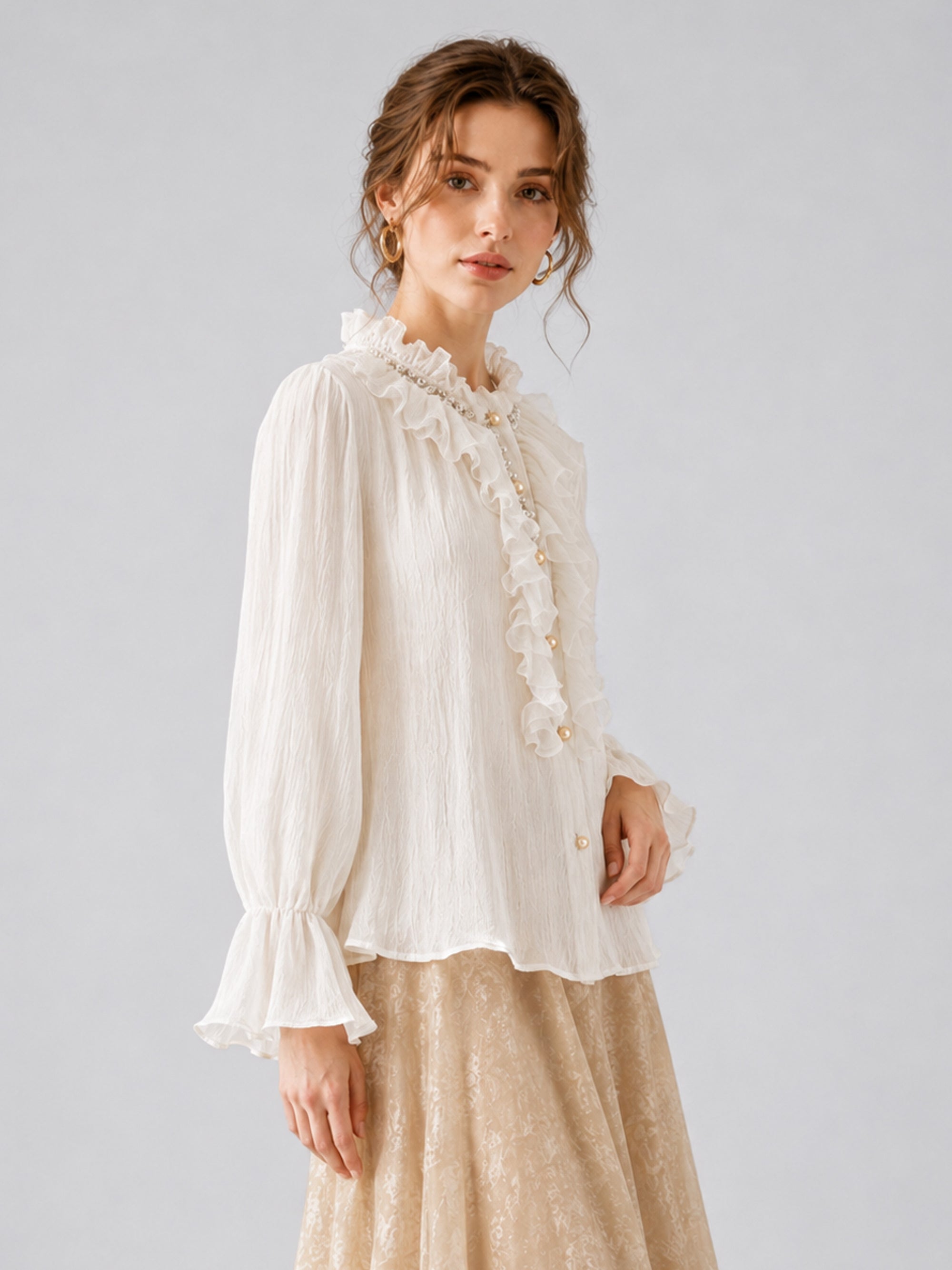 A person models the Social Queen Pearl Embellished Ruffle Collar Blouse, featuring long sleeves, paired with a beige floral skirt against a plain light gray background.