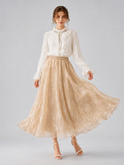 A woman wearing a white ruffled blouse and the Social Queen Jacquard Chiffon Midi Skirt in beige, standing against a plain light background.