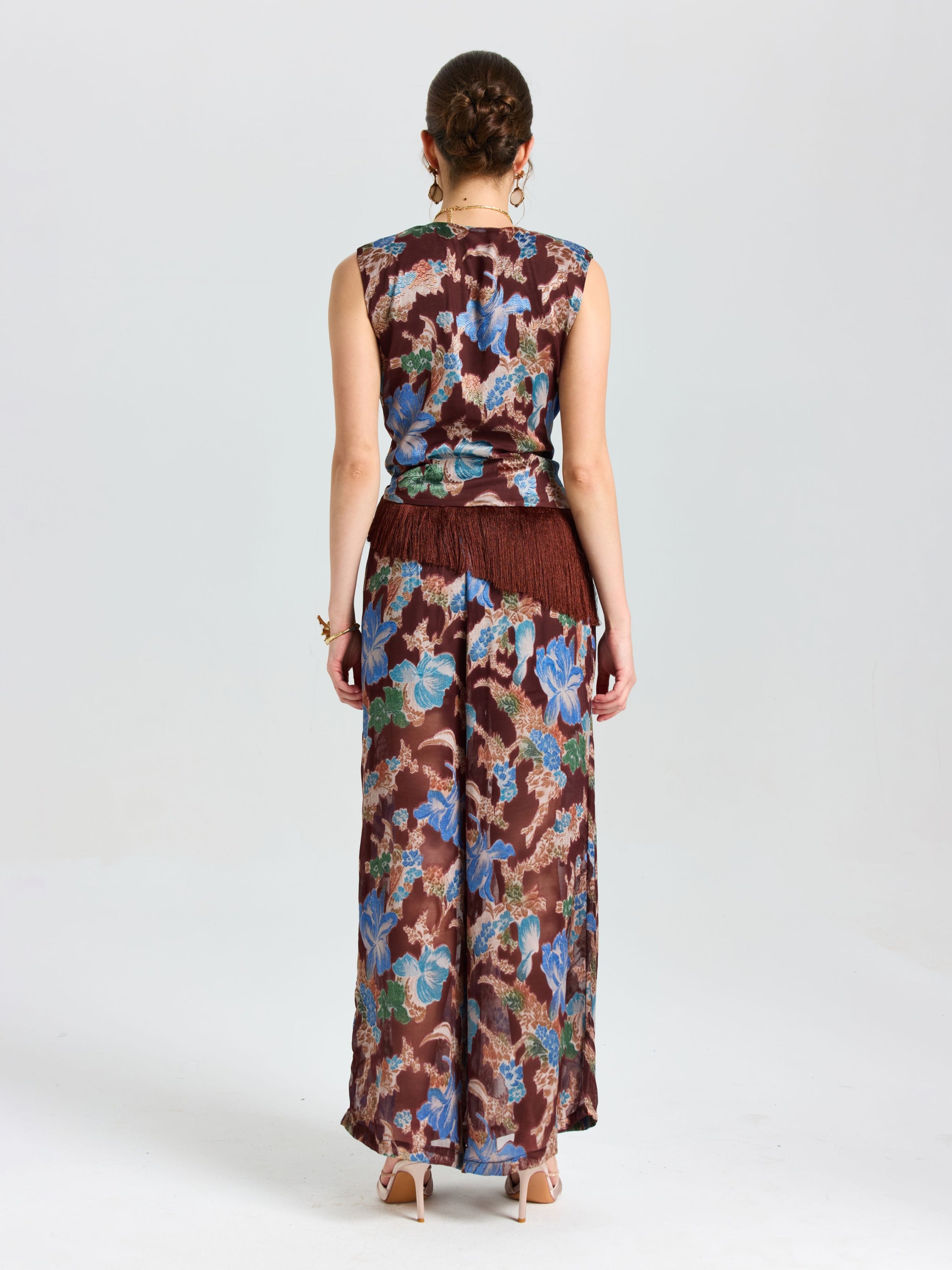 A woman faces away against a white background, wearing the Social Queen Floral Print Fringe Tie-Front Top and matching wide-leg pants.