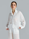 A woman models the Social Queen 3D Lace Appliqué Shirt—a sheer white long-sleeve blouse featuring elegant rose vine lace details—paired with matching white pants, set against a plain gray background.