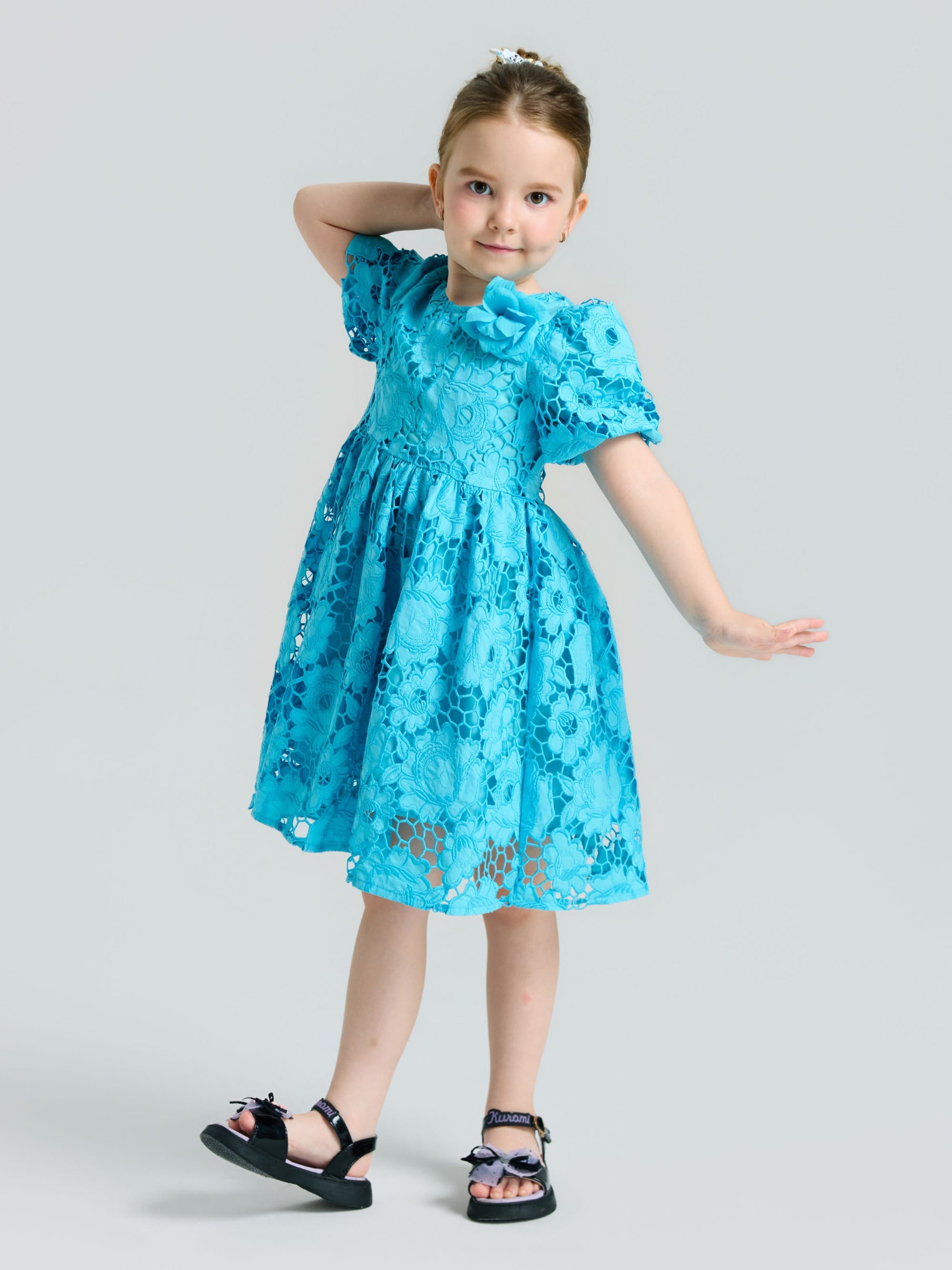 A young girl poses in the Social Queen Girls 3D Floral Appliqué Cutwork Lace Dress, featuring an A-line silhouette and blue lace details, paired with black sandals against a plain background.