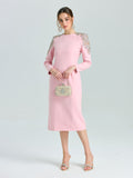 A woman in the Social Queen Crystal Beaded Detail Midi Dress, featuring long sleeves and crystal-embellished shoulders, pairs it with a clutch and high-heeled sandals—ideal evening attire against a plain background.