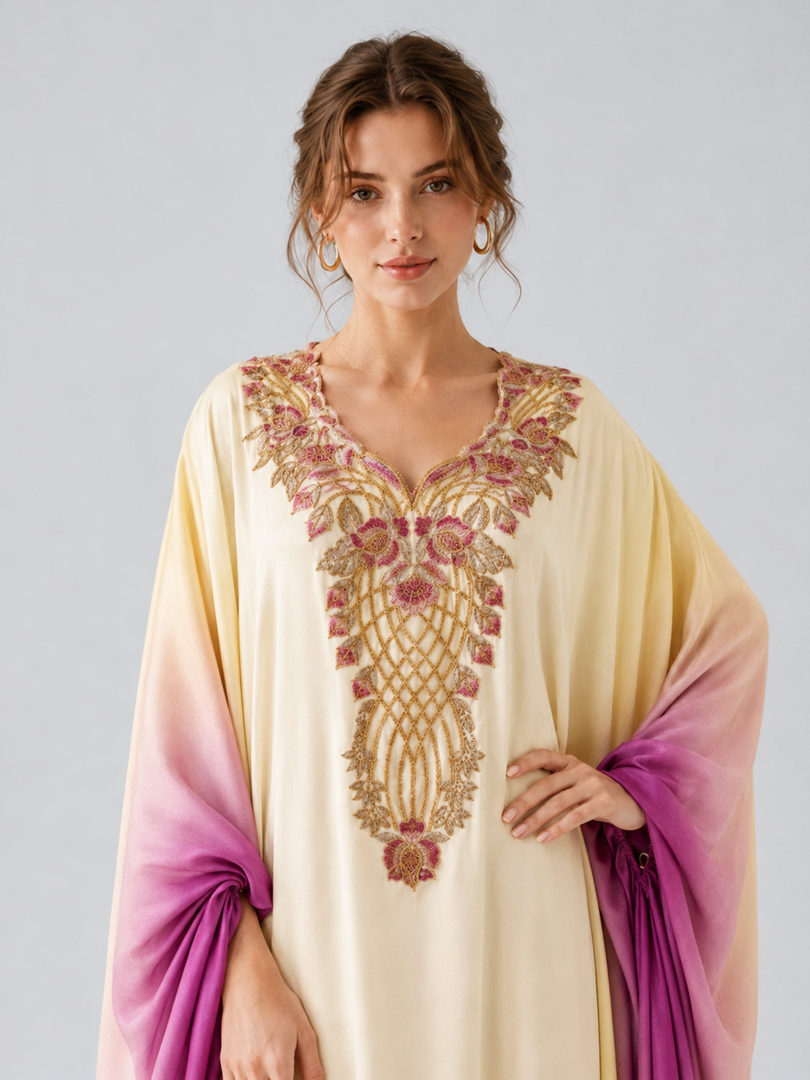 A woman wearing the Social Queen Ombré Beaded Embroidered Cape Dress in cream and purple satin, featuring a gold and pink embroidered neckline, stands against a plain light background.