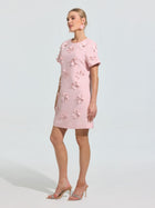 A woman models the Social Queen Beaded Floral Appliqué Dress, an elegant light pink shift adorned with 3D florals—perfect for special occasions.