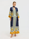 A woman models the Social Queen Moroccan Print Silk Caftan Dress in blue, yellow, and white with gold heels and hoop earrings, standing against a plain white background.