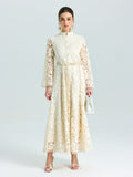 A woman wears the Social Queen Embroidered Lace High-Neck Dress, featuring long sleeves and baroque floral embroidery, paired with a white handbag against a plain light background.