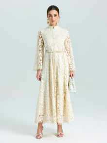 A woman wears the Social Queen Embroidered Lace High-Neck Dress, featuring long sleeves and baroque floral embroidery, paired with a white handbag against a plain light background.