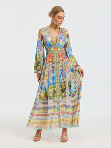 A woman models the Social Queen Garden Print Silk Maxi Dress, featuring a deep V-neck, long sleeves, and a fitted waist, against a plain white background.