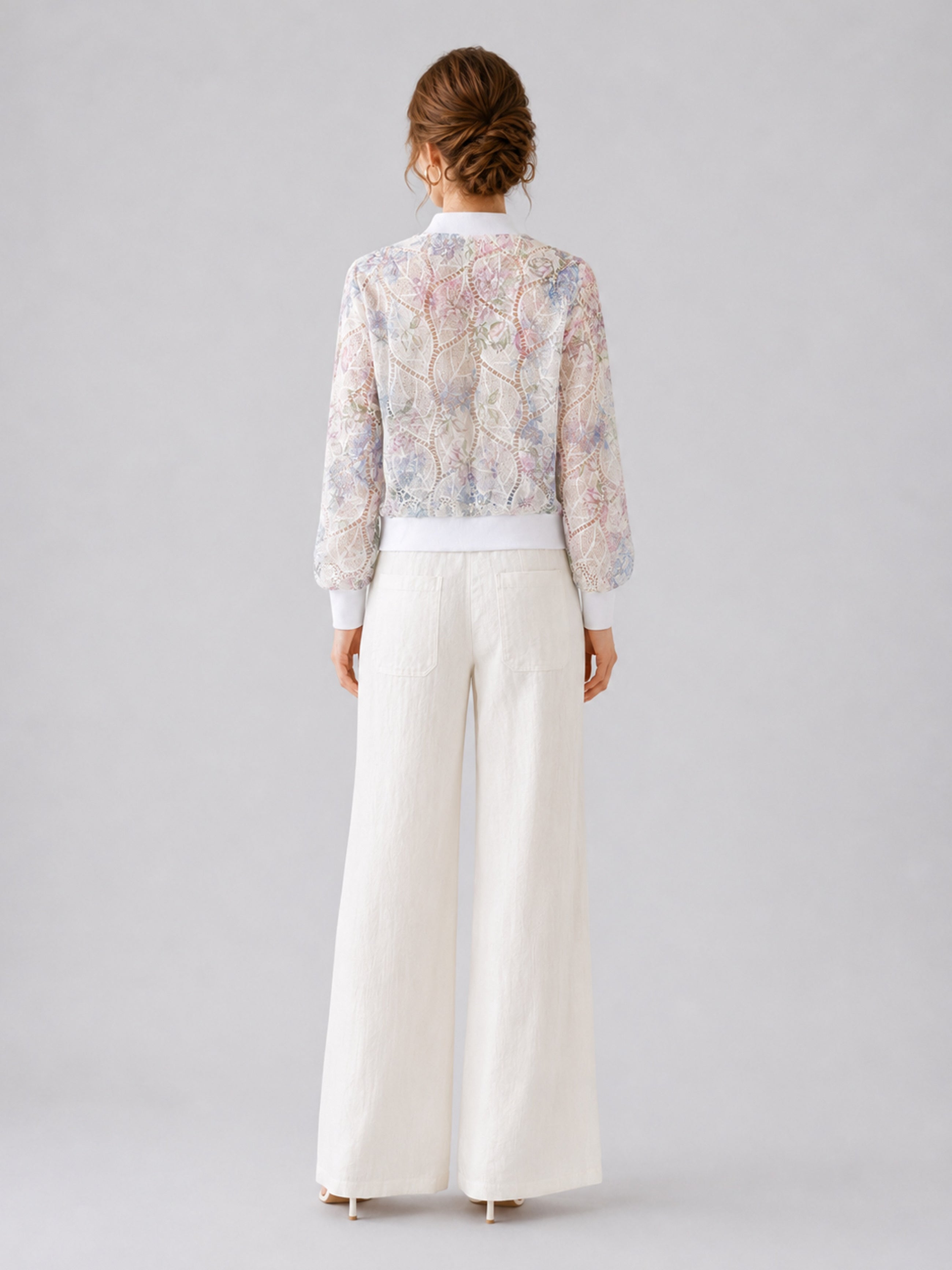 A woman stands with her back to the camera against a plain light gray background, wearing Social Queen’s Casual Wide-Leg Pants with a textured finish and a sheer, patterned blouse.