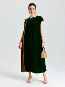 A woman wears the Social Queen Colorblock Silk Velvet Shift Dress with gold drape detail, paired with a small woven handbag and open-toe heels, against a plain light background.
