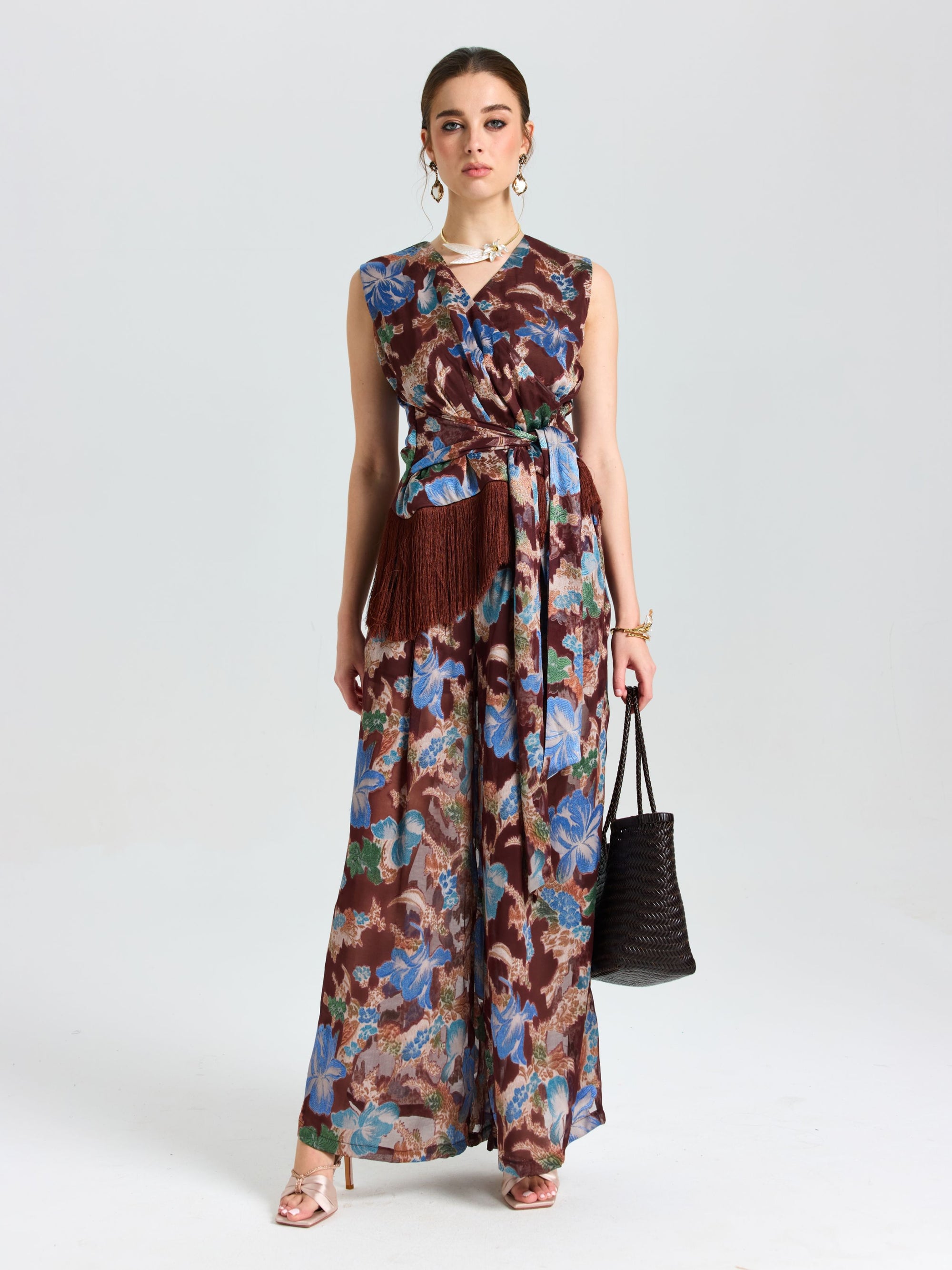 A woman wearing the Social Queen Floral Print Fringe Tie-Front Top stands against a plain white background, holding a black woven bag.