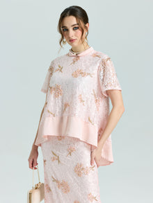 A woman wearing the Social Queen Dragonfly Beaded Lace Top in light pink with floral embroidery and an elegant A-line shape stands against a plain background, holding a beige handbag.