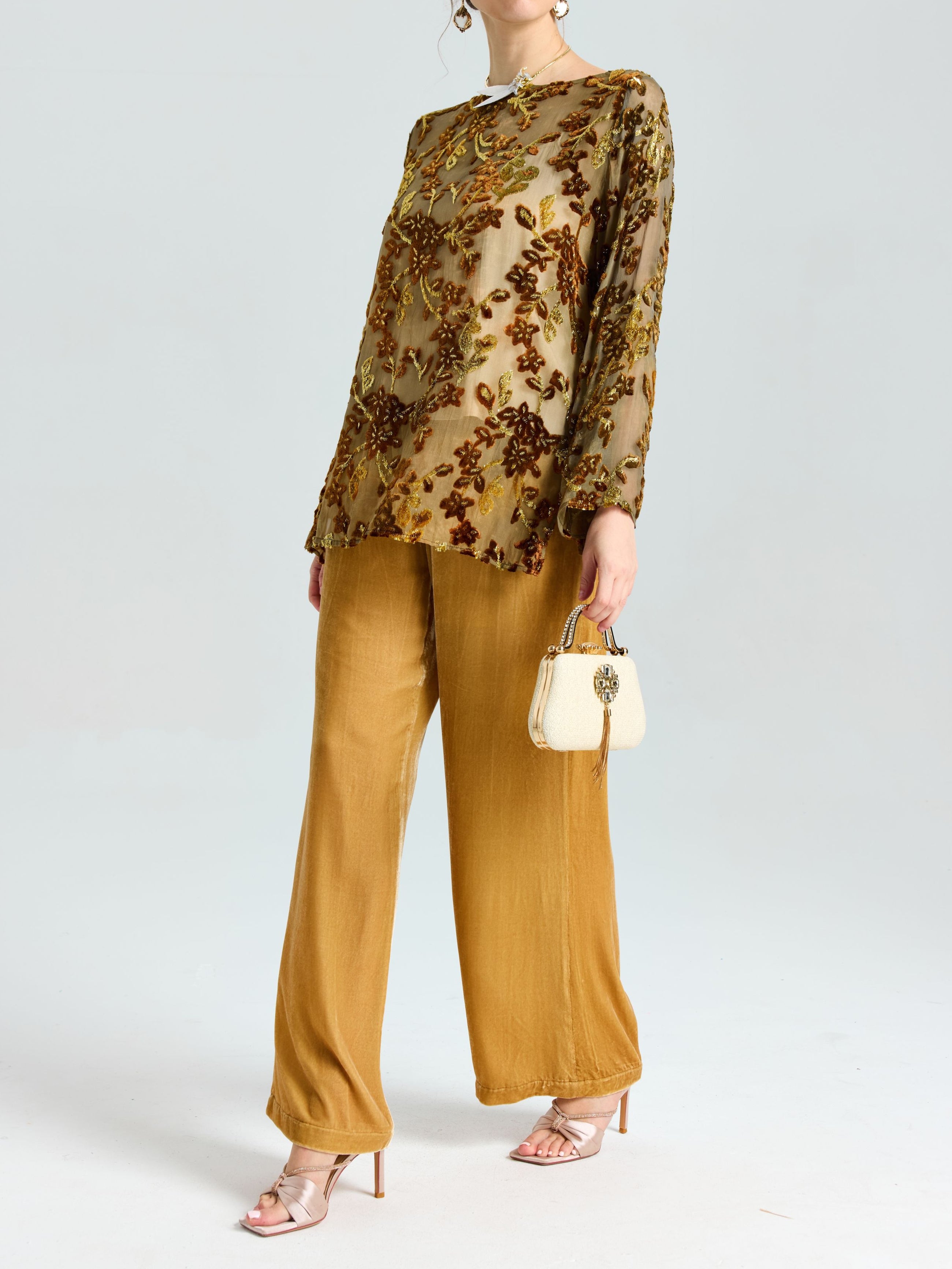A person wears the Social Queen Flocked Floral Silk Sheer Top (Camisole Not Included) styled with gold wide-leg pants, beige heeled sandals, and a small cream handbag, standing against a plain light backdrop.