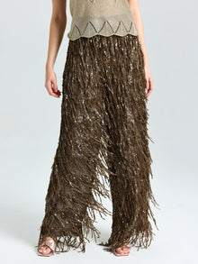 A person wears Social Queen’s Sequin Fringe Wide-Leg Pants, styled with a beige knit top and open-toe sandals.