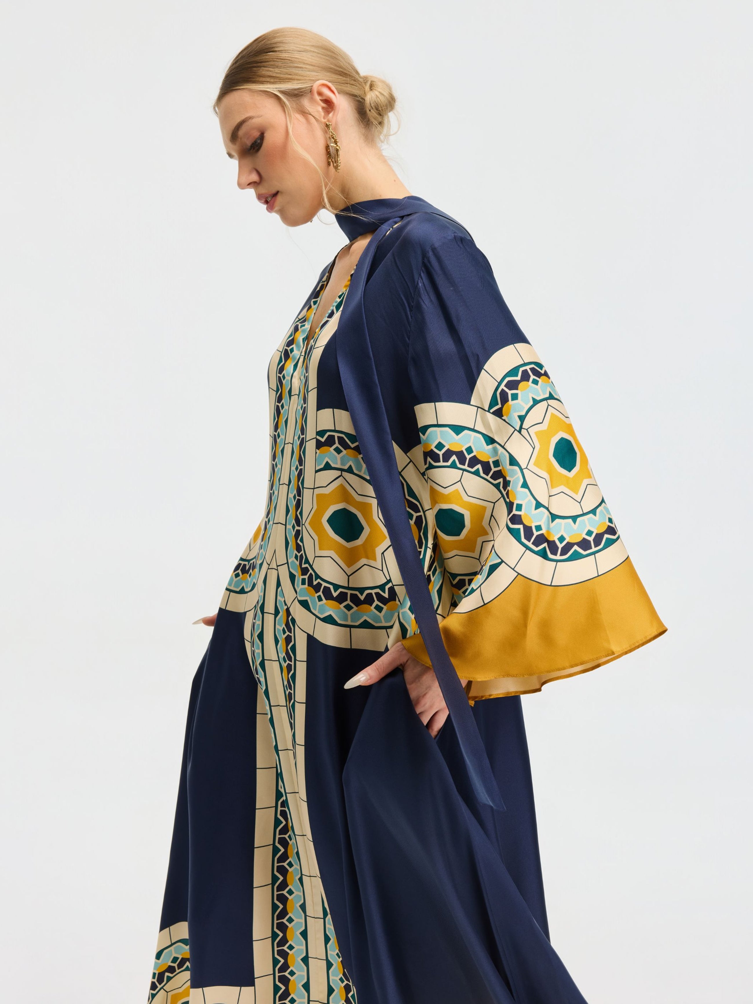 A woman stands in profile against a plain background, wearing the Social Queen Moroccan Print Silk Caftan Dress with matching long outerwear.