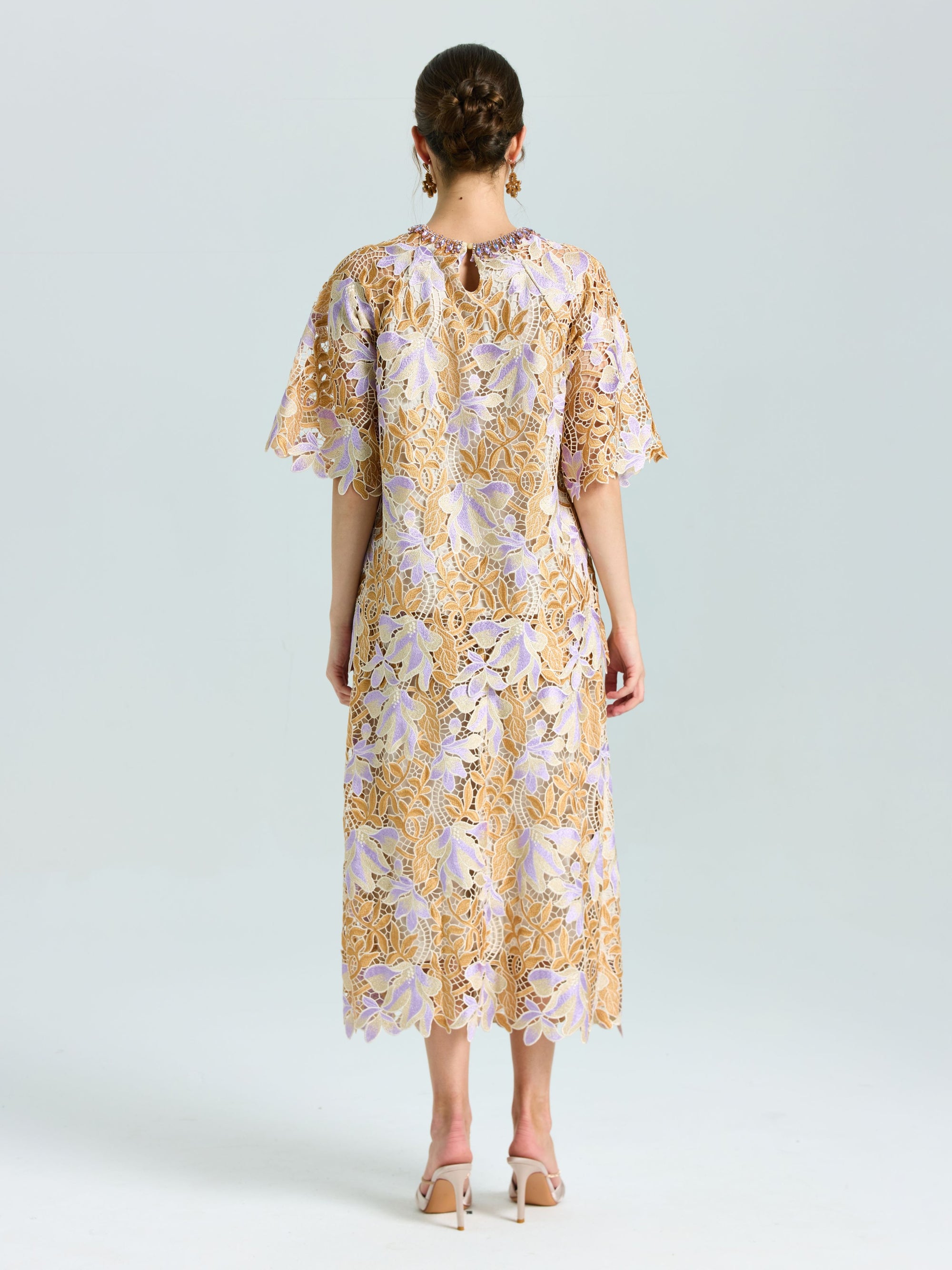 A woman faces away, wearing the Social Queen Floral Embroidered Lace Midi Skirt in beige and lavender with nude heels, set against a plain light background.
