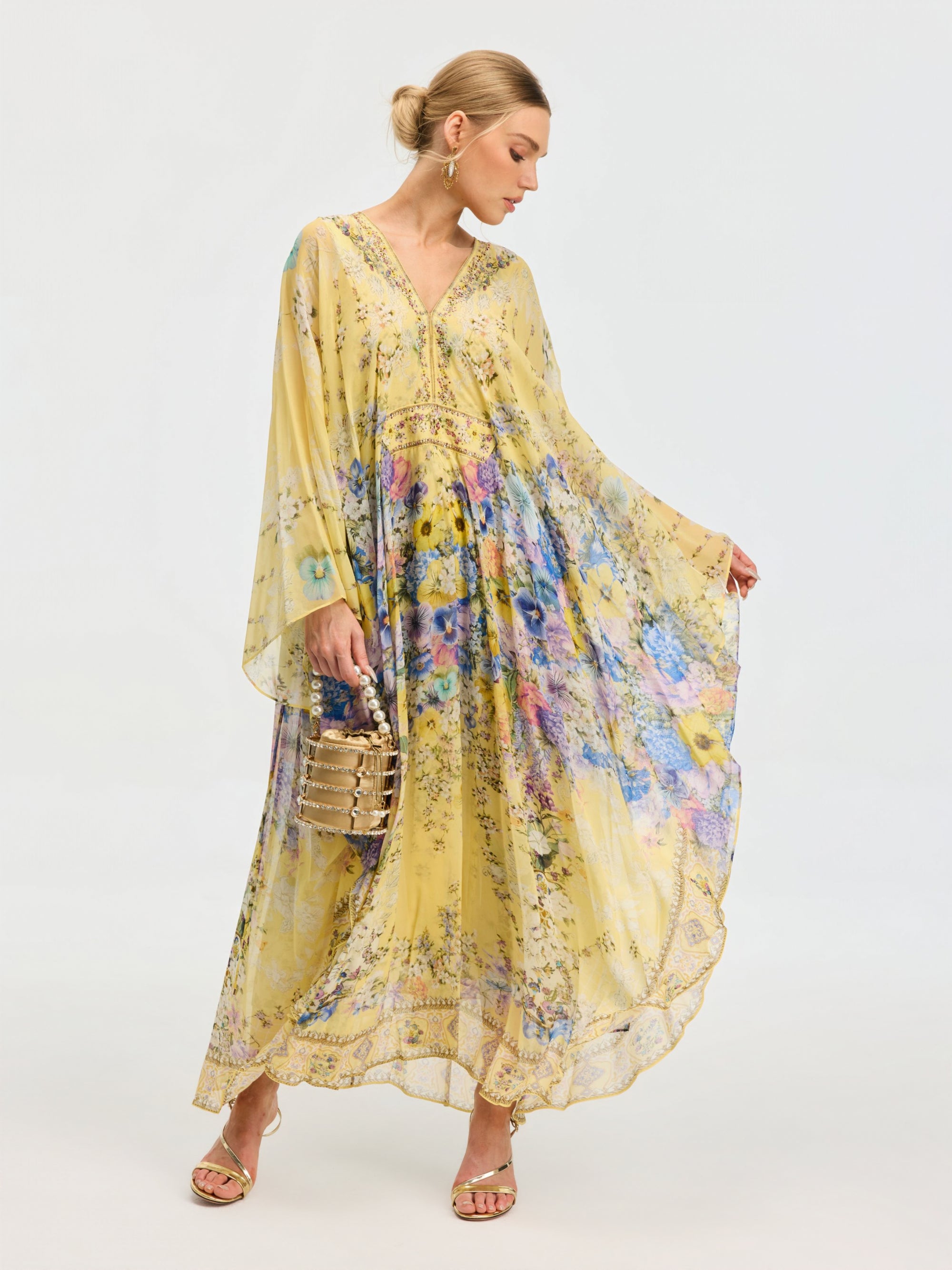 A woman wears the Social Queen Floral Print Silk Caftan Dress, styled with sandals and a small handbag—perfect resort wear—standing against a plain background.