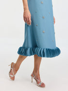 A person models the Social Queen Beaded Crystal Embellished Dress, featuring a shift silhouette, appliqué details, and ruffled hem, styled with silver high-heeled sandals against a white background.