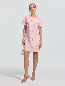 A woman wears the Social Queen Beaded Floral Appliqué Dress in a shift silhouette, paired with high-heeled sandals and a small purse—an ideal occasionwear look.
