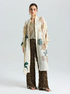 A woman models the Social Queen Floral Embroidered Linen Jacket (Cami Included) with a metallic top and brown fringed pants, posing against a plain white background.