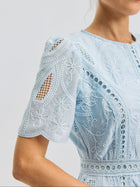 Close-up of a woman wearing the Floral Cutwork Embroidered Dress by Social Queen, crafted in a light blue silk-blend and adorned with floral embroidery, featuring intricate eyelet details and cutouts on the short sleeves.