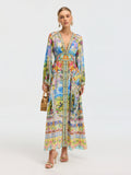 A woman wears the Social Queen Garden Print Silk Maxi Dress, styled with gold sandals, hoop earrings, and a bamboo handbag, set against a plain light background.