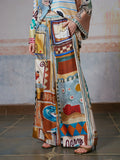 A person wearing Social Queen’s Abstract Print Mulberry Silk Pants with a matching top, featuring a colorful abstract design, stands on a tiled floor with one hand in the pants pocket. The face is out of frame.