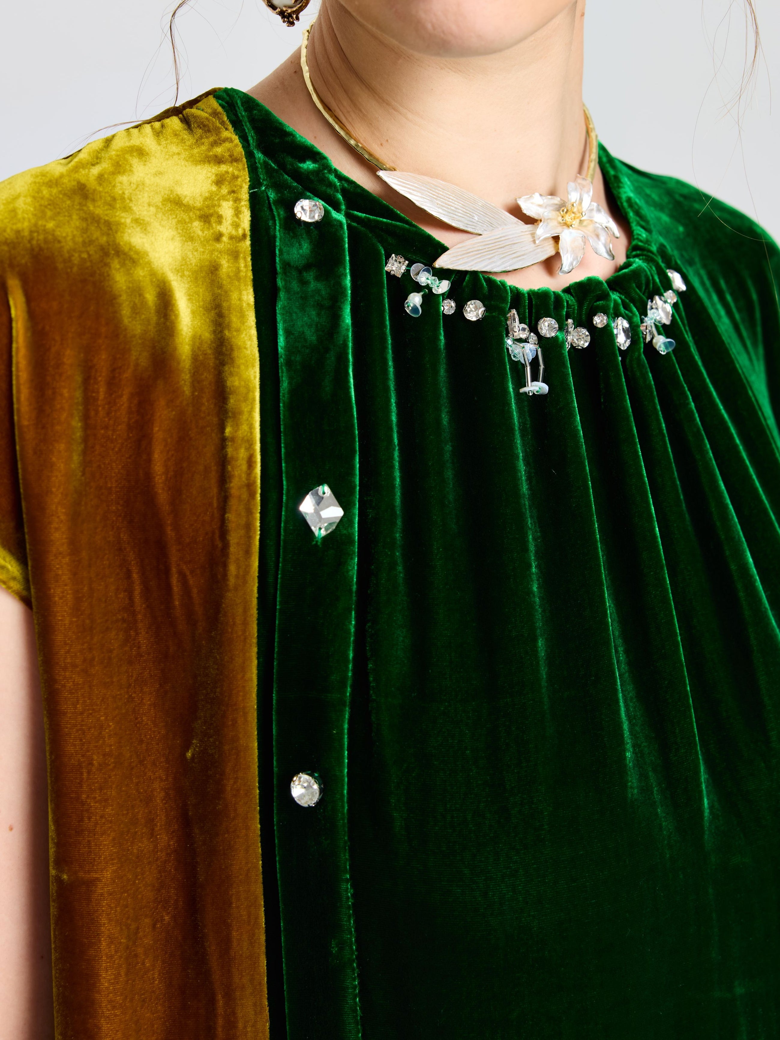 Close-up of a person wearing the Social Queen Colorblock Silk Velvet Shift Dress with crystal embellishments, beaded neckline, and a necklace featuring a white leaf design.