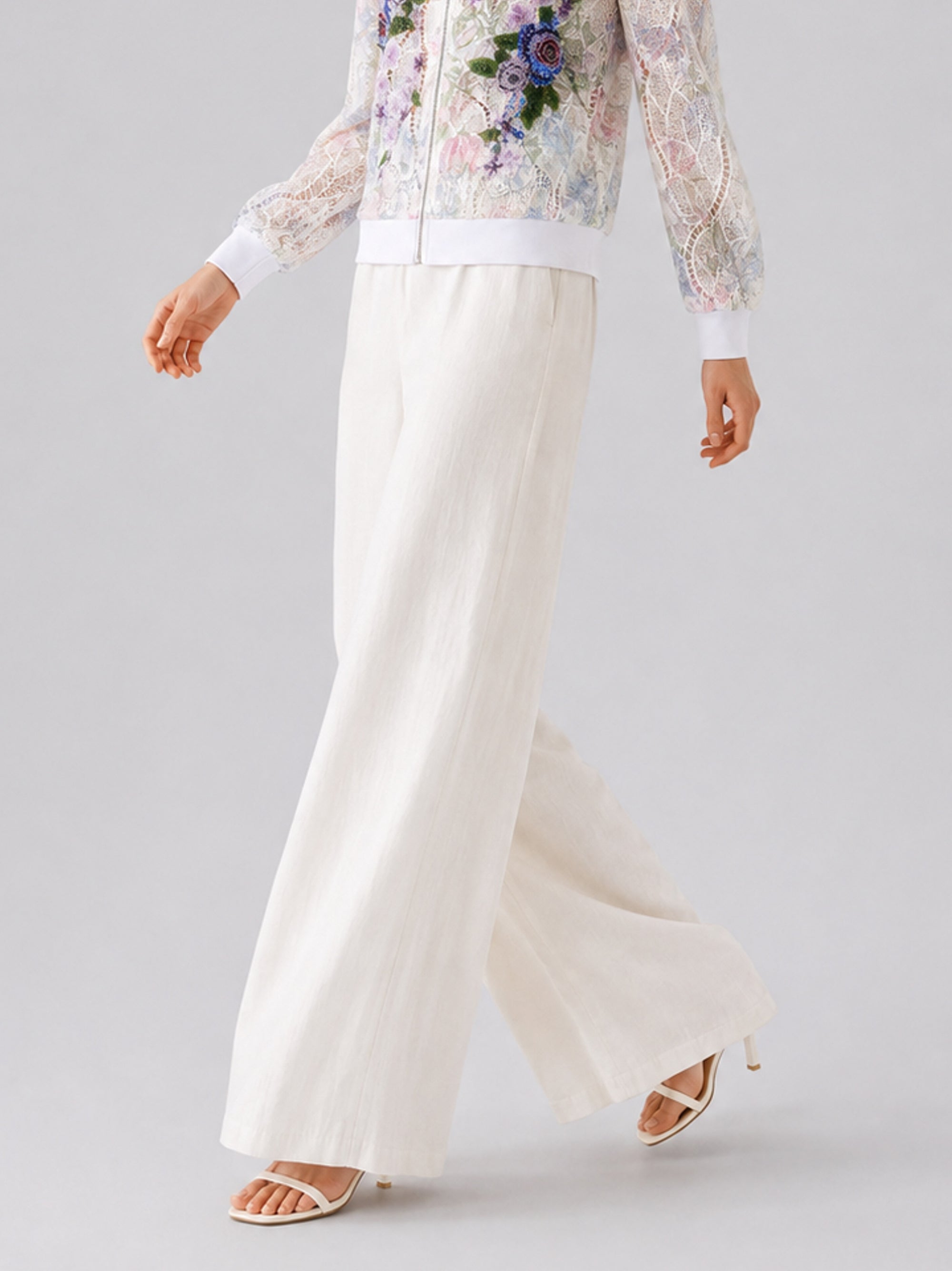 A person wearing Social Queen’s Casual Wide-Leg Pants with a mid-high rise and wide-leg silhouette, paired with a floral lace jacket and white heeled sandals, walking against a light grey background.