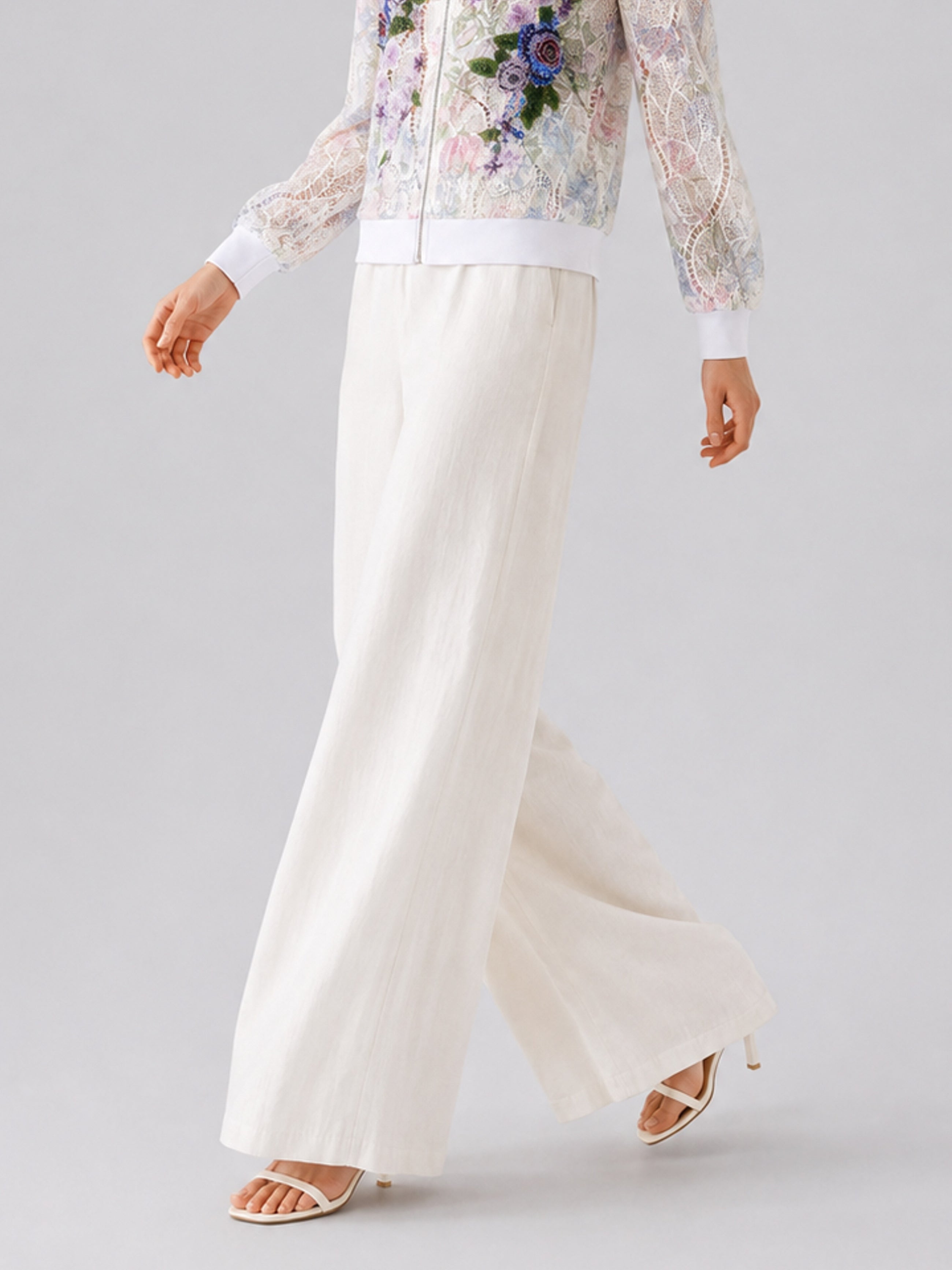 A person wearing Social Queen’s Casual Wide-Leg Pants with a mid-high rise and wide-leg silhouette, paired with a floral lace jacket and white heeled sandals, walking against a light grey background.