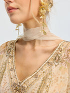 A woman wearing a sheer beige choker, Social Queen Floral Pearl Drop Earrings with a gold-tone finish, and a heavily beaded floral dress with intricate embroidery.