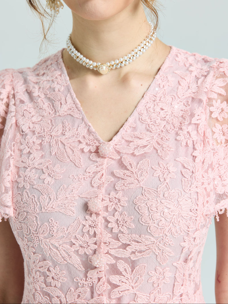 A woman wearing the Social Queen Floral Embroidered Lace Dress with a double-strand pearl necklace.