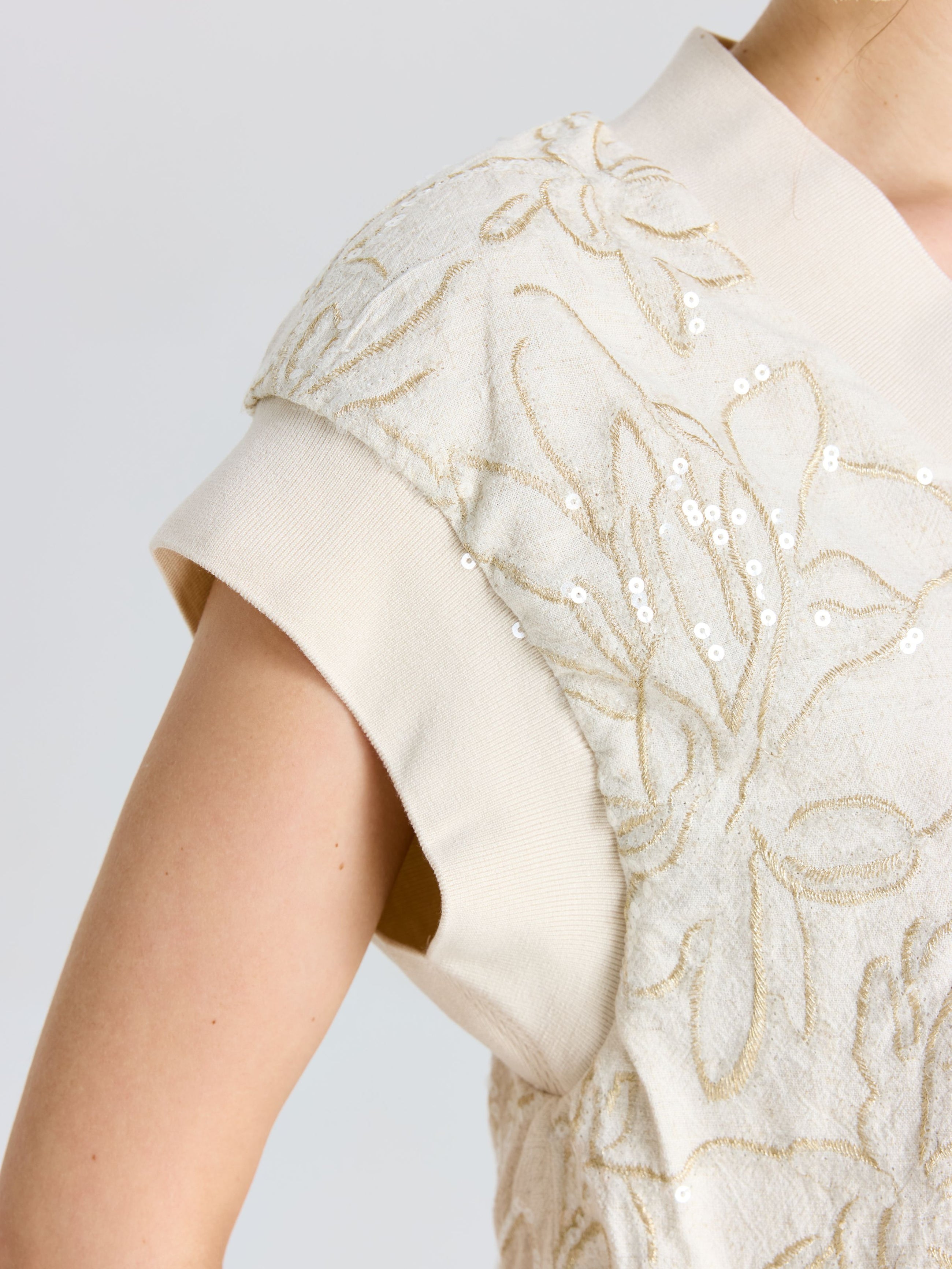 Close-up of a person wearing the Social Queen Floral Embroidered Linen Top, featuring textured floral embroidery, sequin accents, and relaxed batwing sleeves.