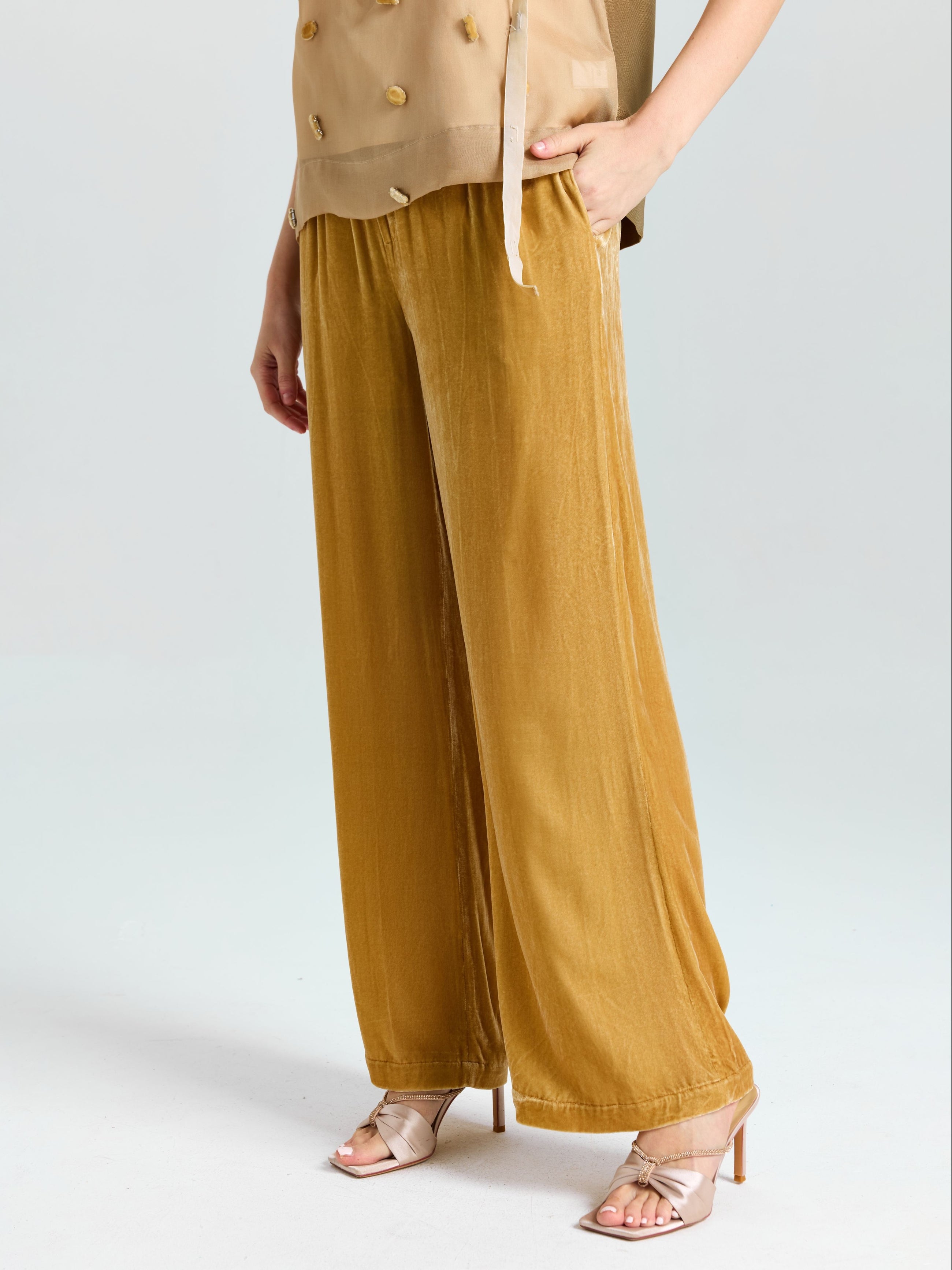 Model wears Social Queen's Silk Velvet Wide-Leg Pants in gold, paired with a beige buttoned sleeveless top and open-toe heeled sandals, standing against a plain light background.