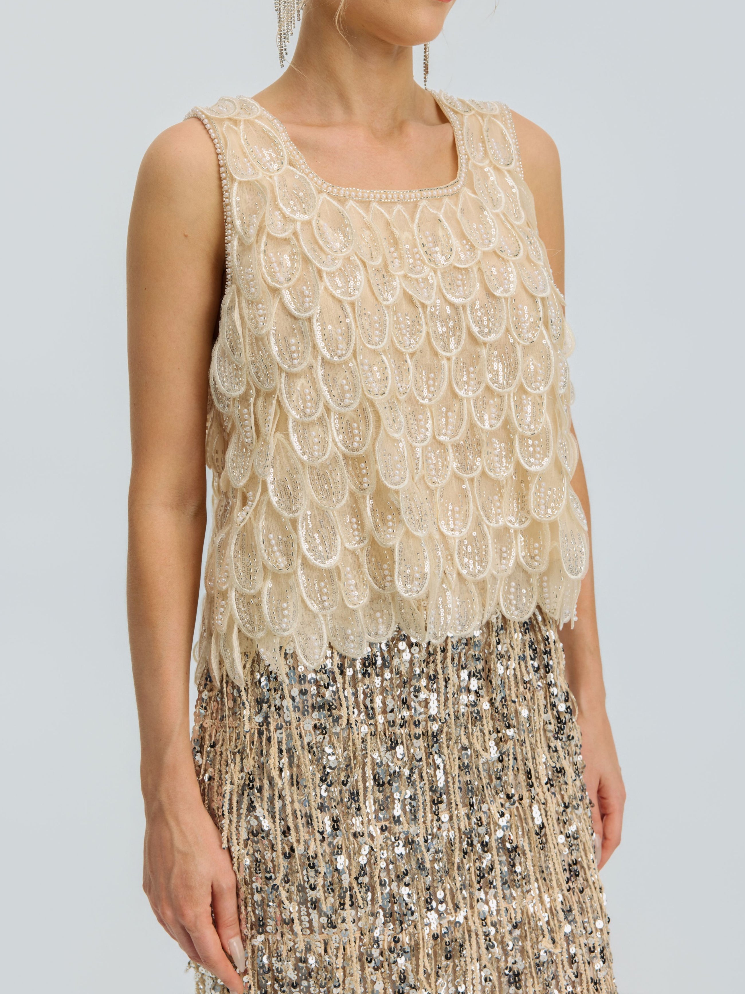 A person wearing the Social Queen 3D Leaf Beaded Mesh Top, a sleeveless style with layered scallop details, paired with a sequined fringe skirt, shown from shoulders to mid-thigh.