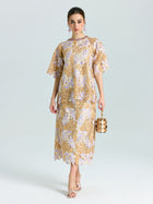 A woman stands against a plain background wearing the Social Queen Floral Embroidered Lace Top, styled with open-toe heels and holding a metallic cylindrical handbag.