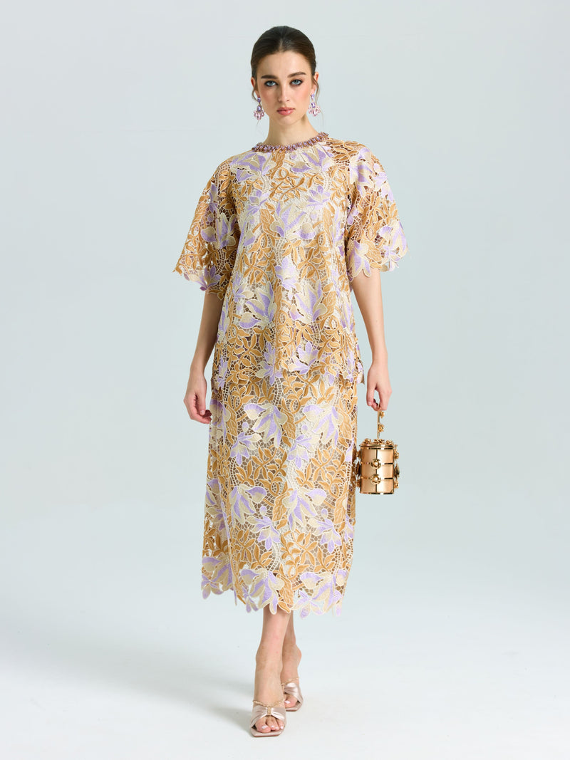 A woman stands against a plain background wearing the Social Queen Floral Embroidered Lace Top, styled with open-toe heels and holding a metallic cylindrical handbag.