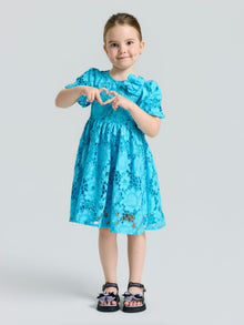 A young girl wearing the Social Queen Girls 3D Floral Appliqué Cutwork Lace Dress and sandals stands against a plain background, forming a heart shape with her hands.