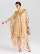 A woman wears the Social Queen Beaded Fringe Cape Dress with sequin embellishments, paired with a beaded purse, matching earrings, and heels, standing against a plain light background.