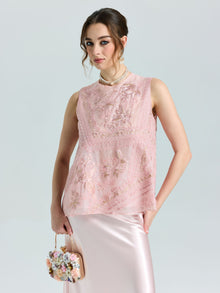 A woman wears the Social Queen Floral Bird Embroidered Silk Top, paired with a satin skirt and pearl necklace, holding a small floral handbag as she poses against a plain background.