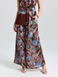 A woman models Social Queen's Floral Print Wide-Leg Pants styled for effortless vacation dressing, pairing gold sandals and standing against a plain background.