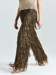 A model showcases Social Queen’s Sequin Fringe Wide-Leg Pants in brown with a beige sleeveless top, walking barefoot against a light background—an eye-catching choice for evening events.