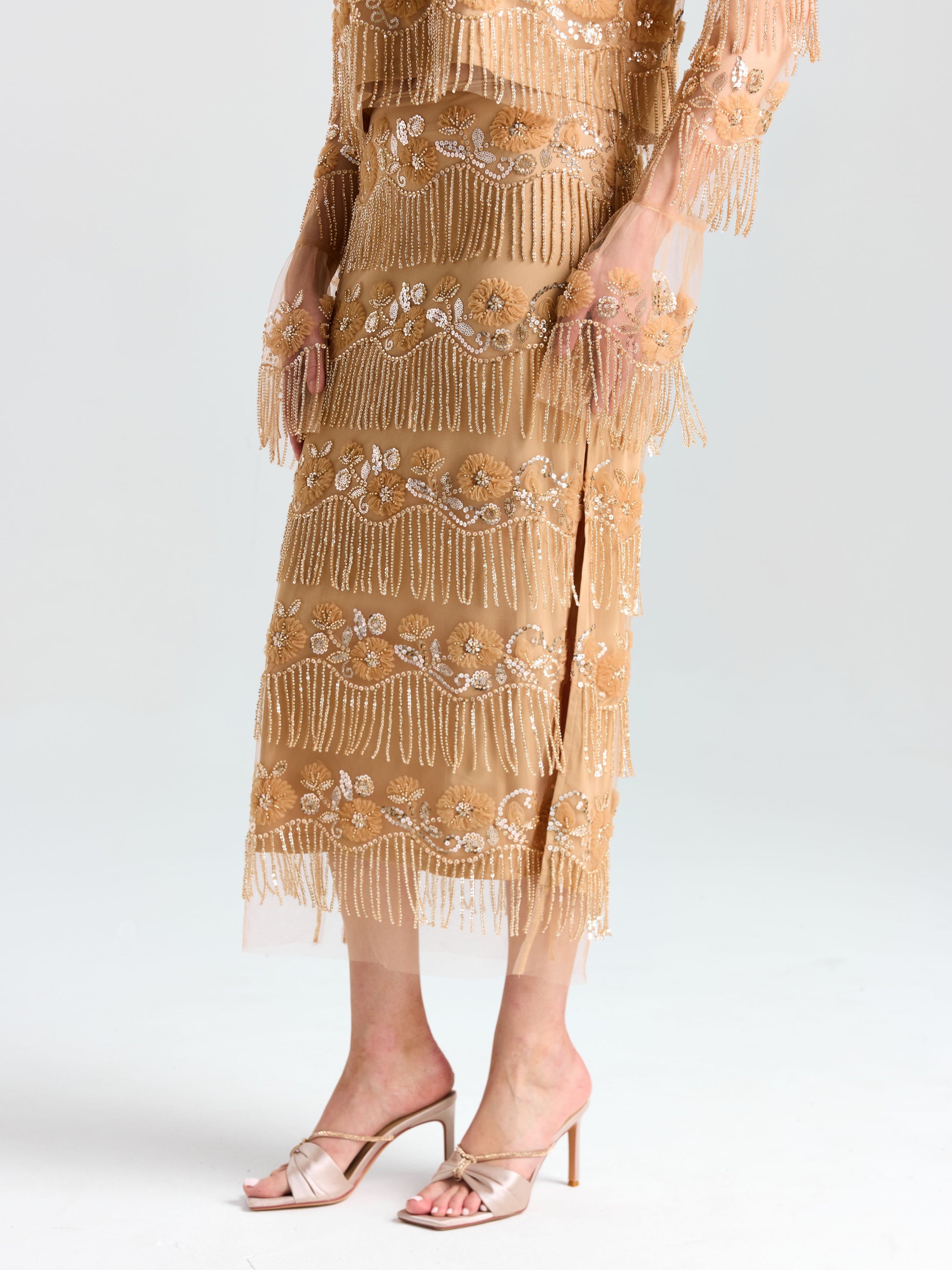 A person wearing the Social Queen Beaded Fringe Slit Midi Skirt and beige open-toe heeled sandals stands against a plain light background.