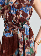 Close-up of a person wearing the Social Queen Floral Print Fringe Tie-Front Top, featuring a sleeveless floral print, side knot, and brown fringe; gold bracelet visible as one hand rests on hip.