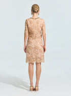A woman stands with her back to the camera in a Social Queen 3D Floral Appliqué Lace Shift Dress—knee-length, light beige, with delicate floral embroidery and half sleeves—paired with gold heels. Ideal as a special occasion dress.